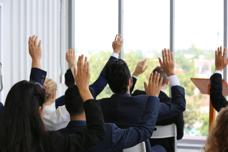 business people in seminar raising hand for vote at meeting acti